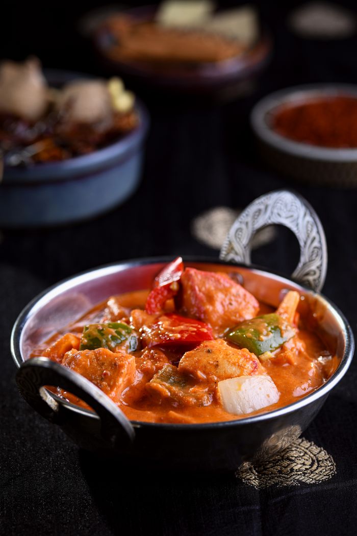 A mouth-watering chicken curry dish with colorful vegetables in an ornate bowl.