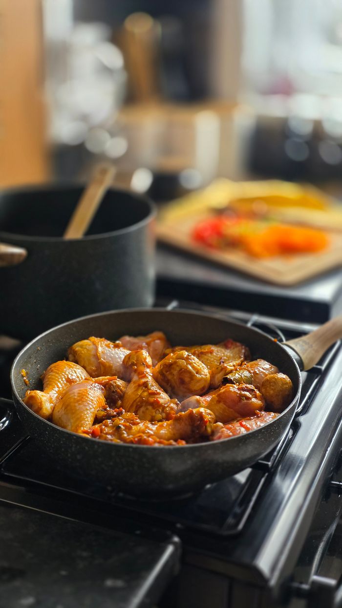 Juicy chicken pieces cooking in a frying pan with herbs and spices, creating a savory meal.