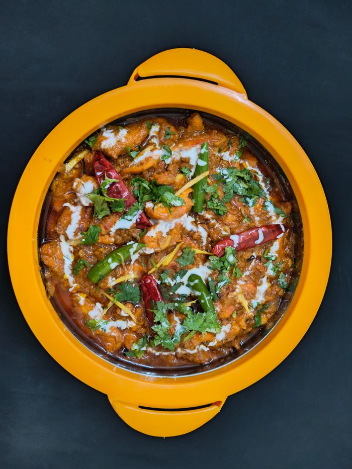 Top view of a flavorful Indian curry garnished with herbs and chilies, served in a vibrant dish.