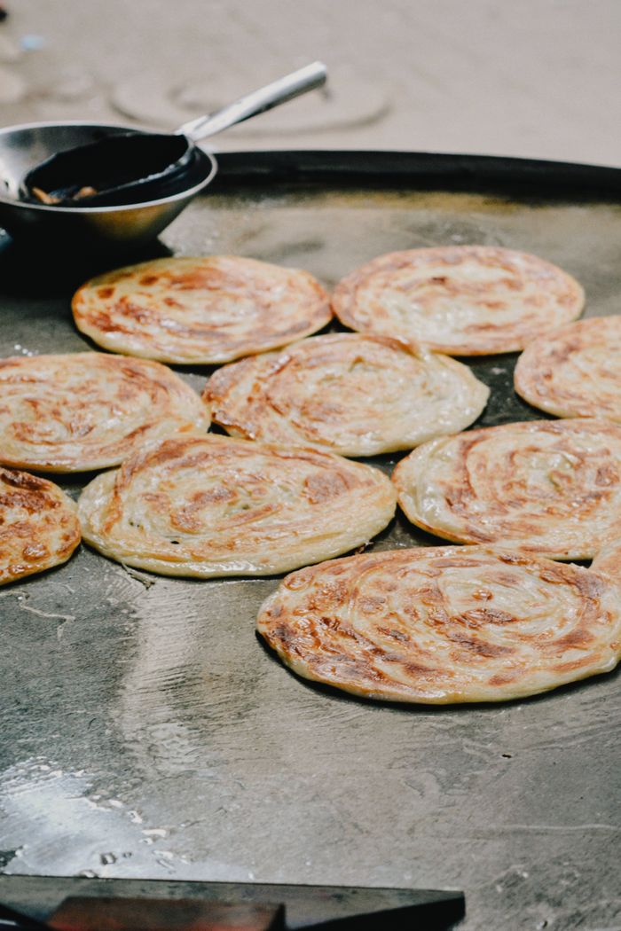 Delicious traditional parathas sizzling on a tawa, capturing authentic South Asian street food culture.
