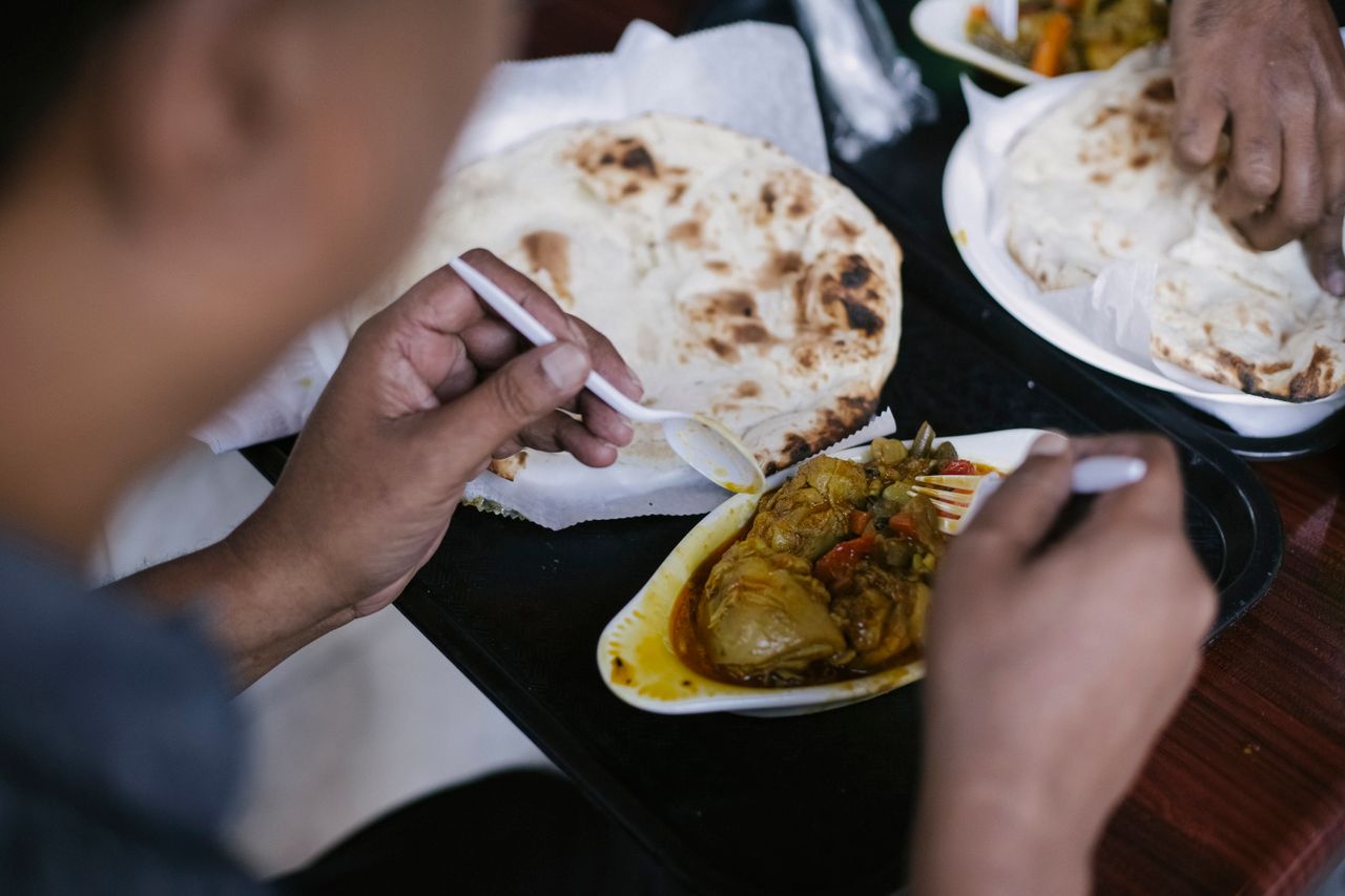 Crop anonymous person eating tasty meat with vegetables and pita for dinner in cafe